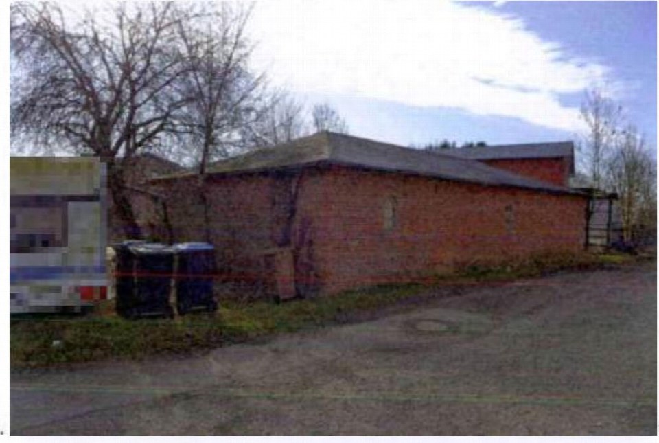 Seitenansicht eines Backsteinbaus mit Dach, umgeben von Bäumen und einem gepflasterten Bereich, Hadenfeld, Landweg 7