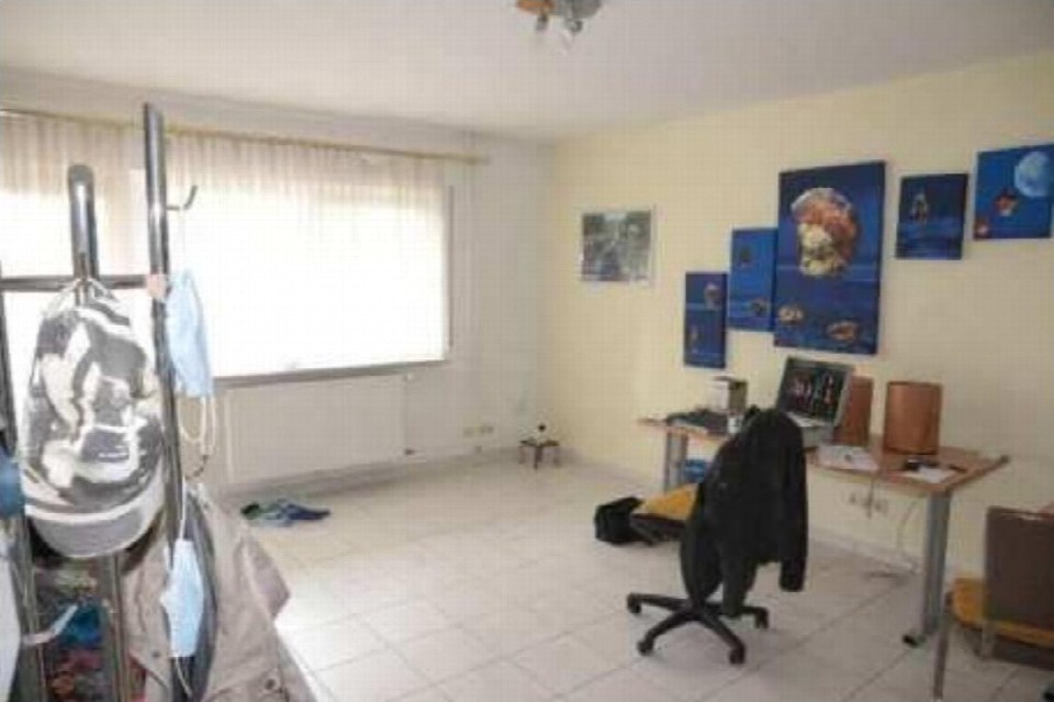 Innenraum mit Schreibtisch, Computer, Wandbildern und Kleiderständer, Fliesenboden, Fenster mit Vorhang