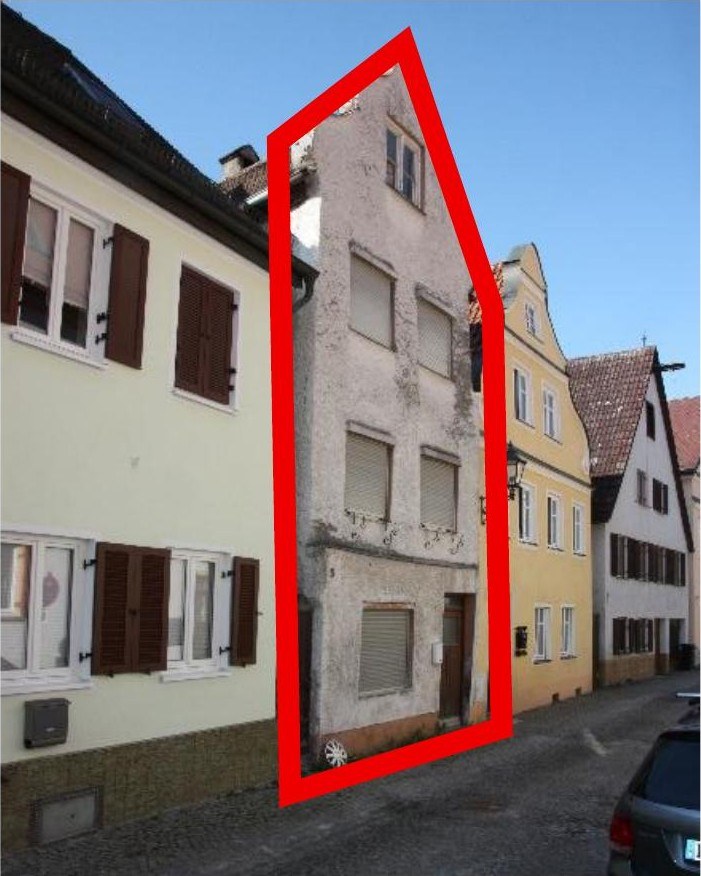 Fassade eines Wohn- und Geschäftshauses in Dillingen, Weberstraße 5, mit mehreren Fenstern und Eingangstür, umgeben von weiteren Gebäuden und Kopfsteinpflaster