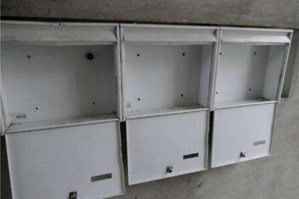 Drei weiße Metallkästen an einer Betonwand, vermutlich in einem Keller oder Technikraum, mit offenen Deckeln und Schließmechanismen