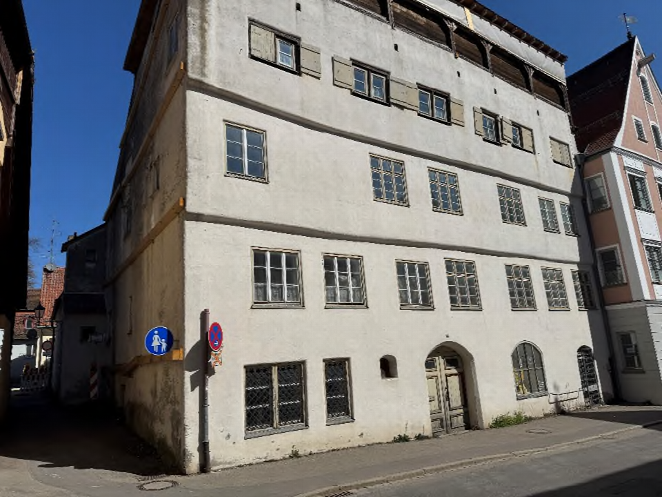 Fassade eines mehrstöckigen Gebäudes an der Ecke Zangmeisterstr. 26 in Memmingen, mit Fenstern, Türen und Straßenzeichen