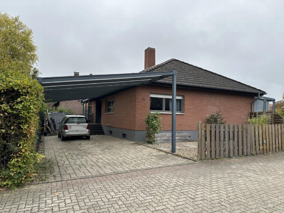 Einfahrt mit Pflastersteinen, Carport und geparktem Auto vor einem Backsteinhaus in Rötgesbüttel, Lehmring 13