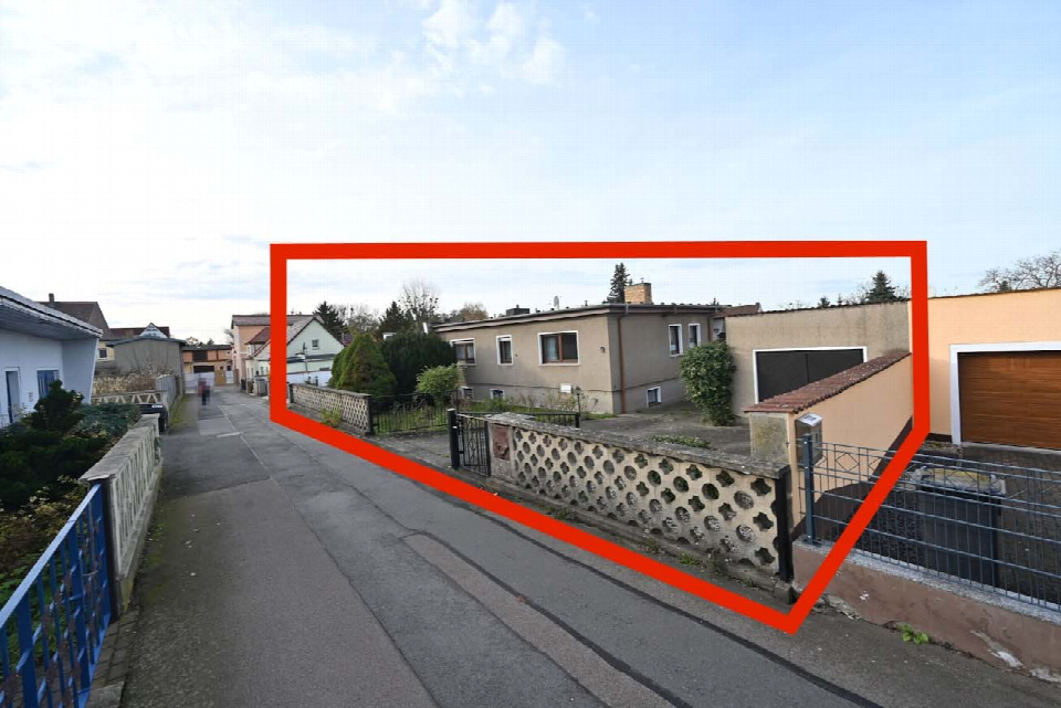 Straßenansicht eines Wohngebäudes mit Vorgarten und Zaun
