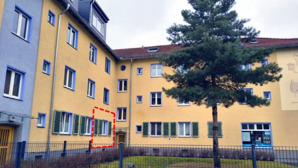 Gelbes Wohngebäude mit Fenstern, Baum und Zaun