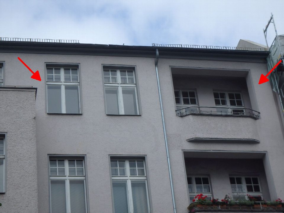 Fassade eines mehrstöckigen Gebäudes mit Fenstern und Balkon