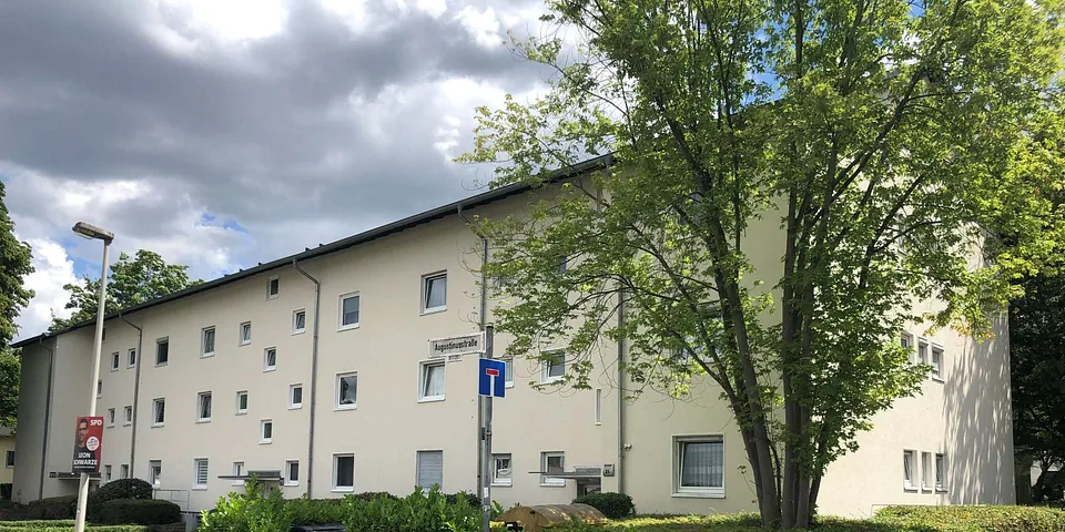 Seitenansicht eines mehrstöckigen Wohngebäudes in Bonn, Augustinusstraße, mit Fenstern, Dachrinnen und Bäumen im Vordergrund