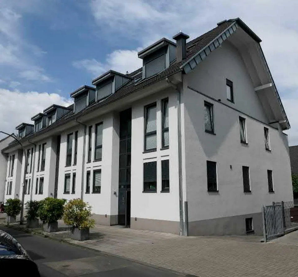 Fassade eines Mehrfamilienhauses mit Dachgauben, Fenstern und Eingangstür an der Longericher Hauptstr. 56 in Köln