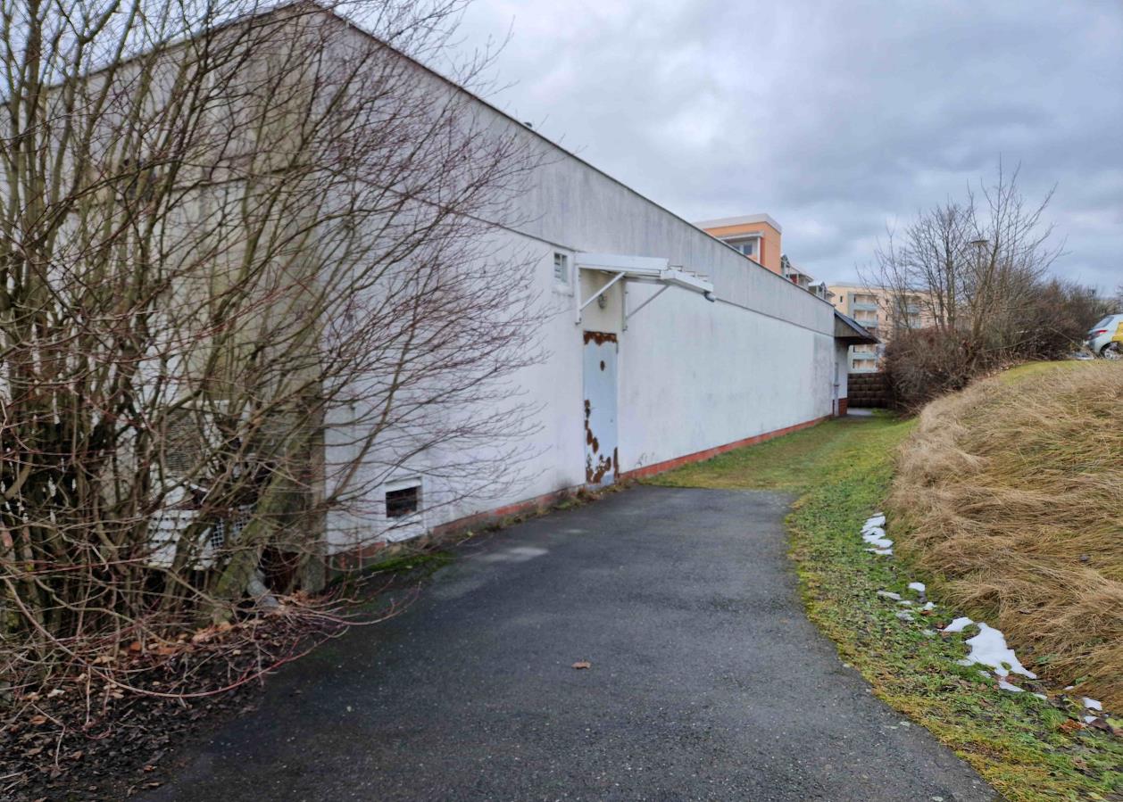 Seitenansicht eines weißen Gebäudes an der Clemens-Schiffel-Straße 8 in Marienberg, 09496, mit asphaltierter Zufahrt, kahlen Sträuchern und vereinzeltem Schnee am Hang