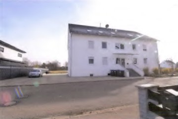 Vorderansicht eines weißen Mehrfamilienhauses in Ellwangen, Ipfstraße 38, mit Eingangstreppe und Fenstern, geparktem Auto vor dem Gebäude