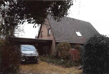 Garage mit überdachtem Stellplatz für ein Fahrzeug vor einem Einfamilienhaus in Husum, Altenwunge 1. Umgeben von Sträuchern und Bäumen