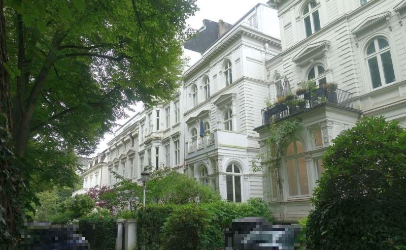 Fassade einer Wohnhauszeile in Hamburg-Rotherbaum, Heimhuder Straße 13, mit weißen Putzfassaden, Erkern und Balkonen, umgeben von Bäumen und Sträuchern
