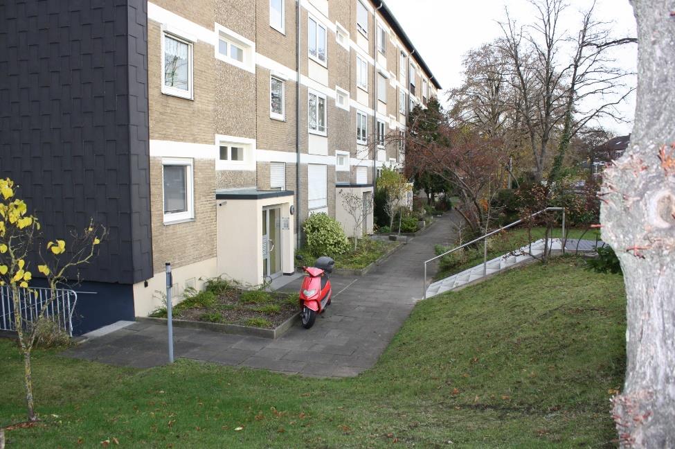 Gartenbereich mit Rasen, Bäumen und einem Gehweg vor einer Mehrfamilienwohnung in Monheim am Rhein, Am Sportplatz