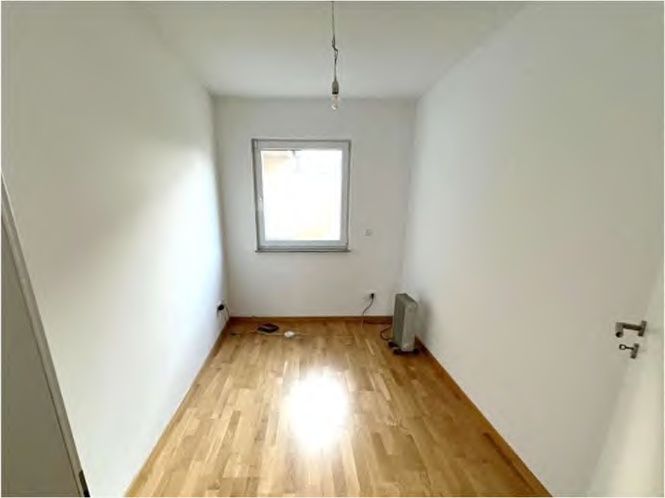 Leeres Schlafzimmer mit hellem Holzboden, weiß gestrichenen Wänden, einem Fenster und einer hängenden Leuchte. Im Kornfeld 11, 63691 Ranstadt
