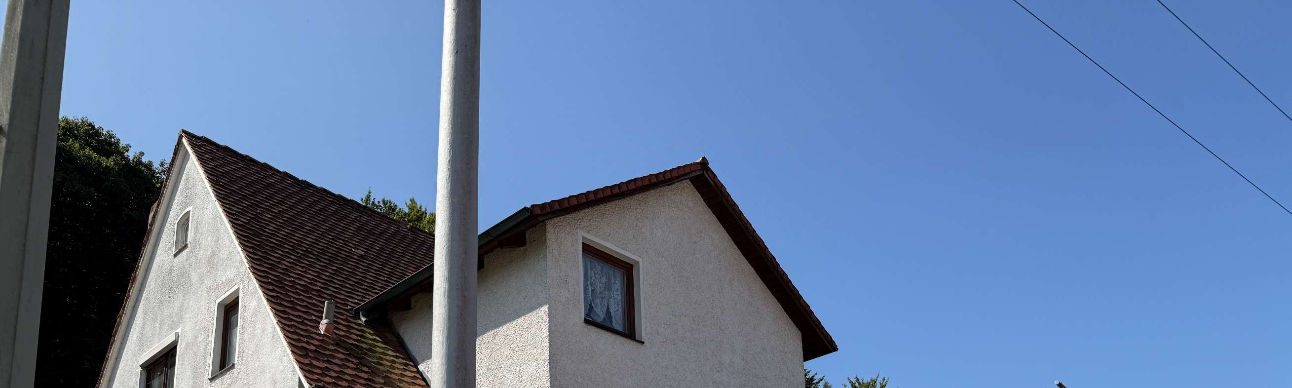 Außenansicht der Doppelhaushälfte in Nittendorf, Glockenstraße 8a, mit weiß verputzter Fassade, braunem Satteldach und Fenstern unter klarem Himmel