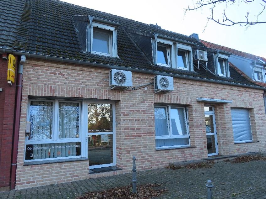 Fassade eines Wohn-/Geschäftshauses mit Eingang, Fenstern, Dachgauben und Außenklimaanlagen