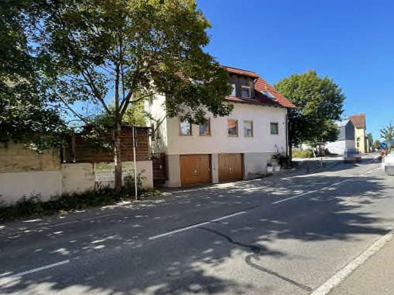 Seitenansicht eines zweistöckigen Gebäudes mit rotem Satteldach und Holztoren im Erdgeschoss an der Herrenberger Straße 43 in Ammerbuch, 72119. Bäume und Straße im Vordergrund