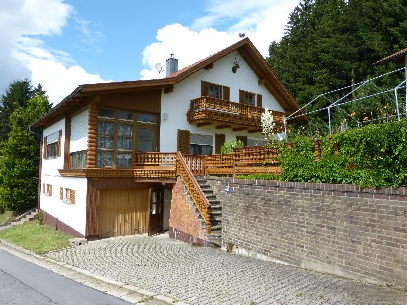 Einfamilienhaus in Waldkirchen, Im Ebenfeld 8, mit weißer Fassade, Holzverkleidung, Balkonen und Eingangstreppe, umgeben von Grünanlagen und Bäumen