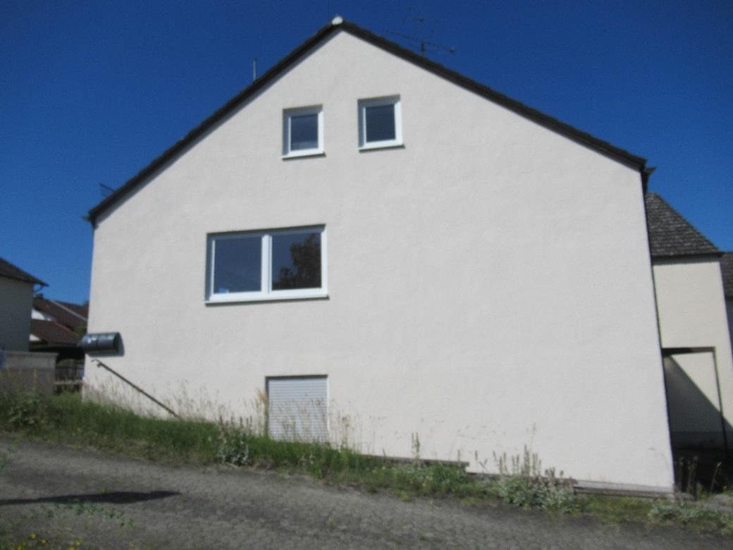 Seitenansicht eines Mehrfamilienhauses in Altmannstein-Steinsdorf, Salvatorweg 8, mit weiß verputzter Fassade, Dachgauben und Fenstern unter klarem Himmel
