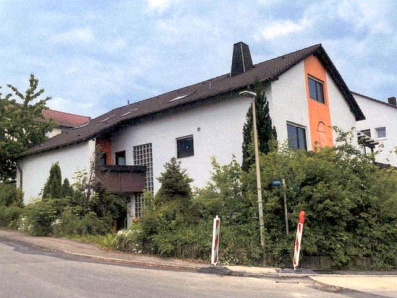 Zweistöckiges weißes Gebäude mit orangefarbener Fassadenecke, dunklem Dach und Fenstern, umgeben von Grünanlagen, in Burgstetten-Burgstall, 71576, Wohnfläche EG ca. 122