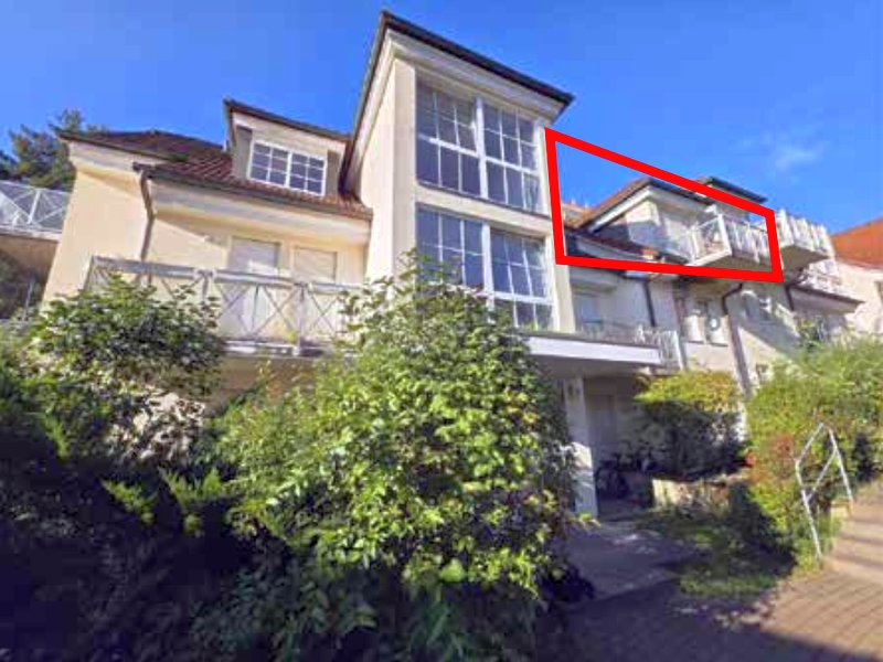 Einfamilienhaus in Königs Wusterhausen, Berliner Straße 19f, mit mehreren Fenstern, Balkon und umgebenden Sträuchern unter klarem Himmel