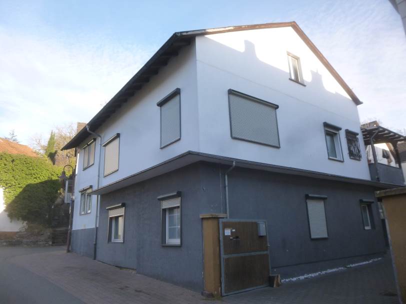 Zweifamilienhaus in Wetzlar, Hohelindstraße 4, mit weißer Ober- und grauer Untergeschossfassade, Fenstern mit Jalousien und Eingangstür im Erdgeschoss