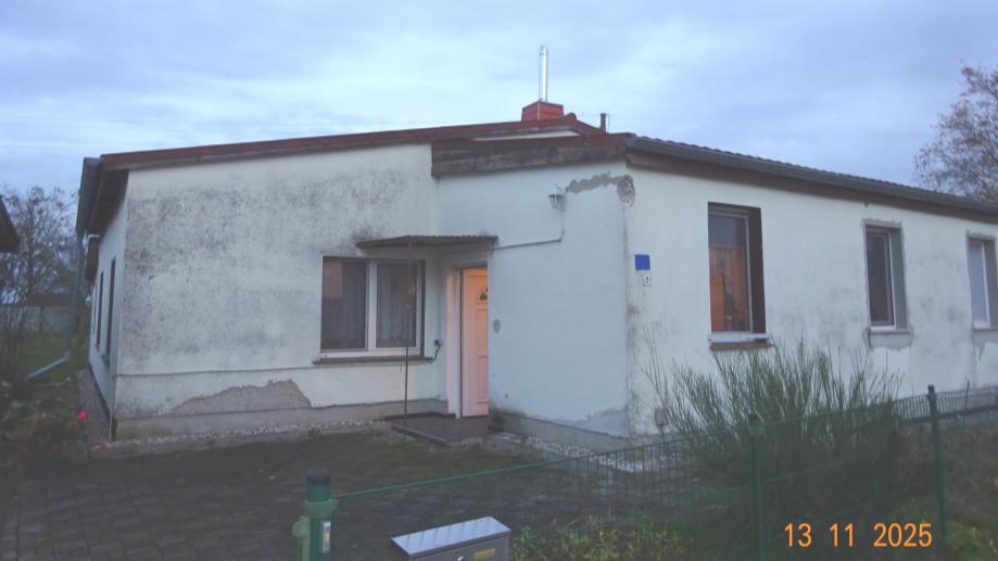 Einfamilienhaus in Löbnitz, Teichstraße 2, mit weißer Fassade, braunen Fensterrahmen und Eingangstür, umgeben von Grünfläche und Zaun