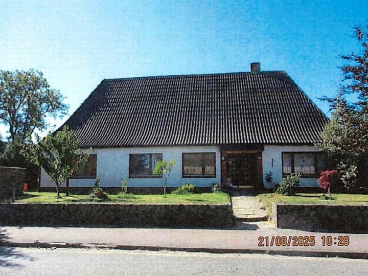 Einfamilienhaus mit dunklem Wellblechdach, weiß verputzten Wänden und Vorgarten, Hauptstraße 33, Stapel, 25879