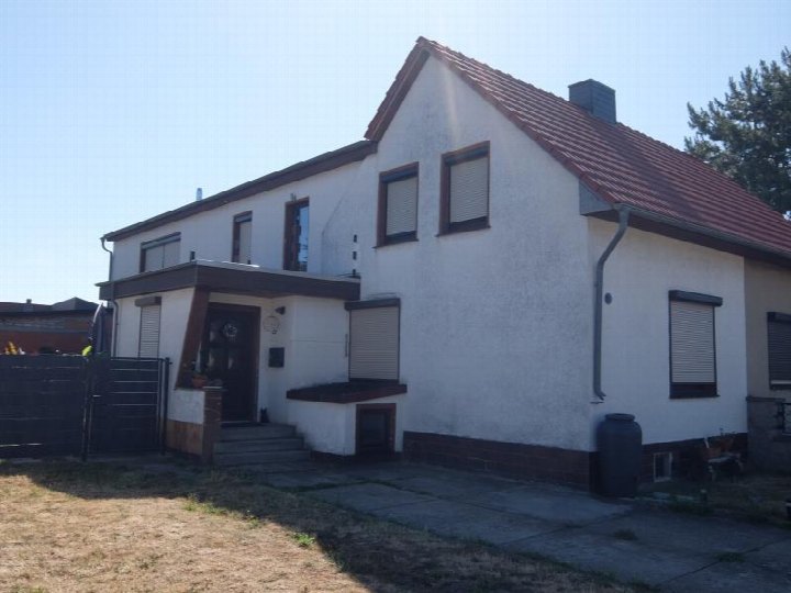 Vorderansicht einer Doppelhaushälfte in Blankenburg, Finkenweg 20, mit weiß verputzter Fassade, rotem Ziegeldach und Eingangsbereich mit Stufen