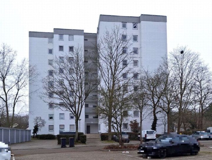Fassade eines weißen Mehrfamilienhauses in Limburgerhof, Schlesier Straße 14, mit kahlen Bäumen und geparkten Autos vorne