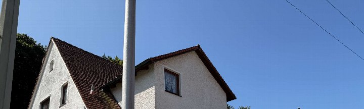 Außenansicht der Doppelhaushälfte in Nittendorf, Glockenstraße 8a, mit weiß verputzter Fassade, braunem Satteldach und Fenstern unter klarem Himmel