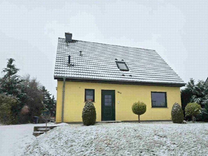 Gelbes Einfamilienhaus mit schwarzem Satteldach, verschneiter Vorgarten, grüner Haustür und Fenstern, Dorstr. 29, Malchin OT Scharpzow