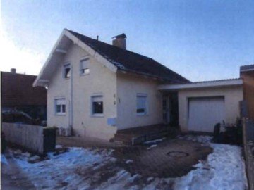 Einfamilienhaus in Landau a. d. Isar, Closenstraße 4, mit schräger Dachform, beigefarbener Fassade, Eingangstreppe und Garagenanbau; Schnee auf dem Vorgarten und Gehweg