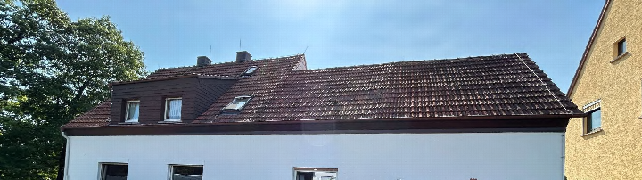 Dachansicht eines Gebäudes in Wetzlar, Zielhausweg 11, mit braunen Ziegeln, Dachgauben und einem Anbau mit Fenstern unter klarem Himmel
