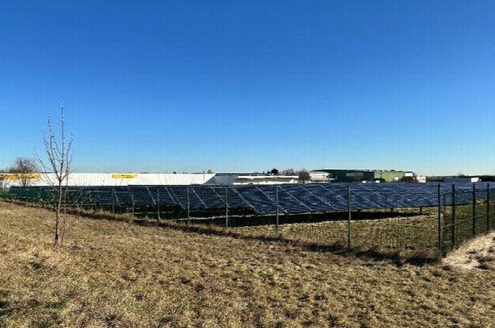 Solaranlage auf einem Feld in Emersleben, Bruchweg, 38822, unter klarem blauen Himmel, umgeben von einem Zaun, im Hintergrund Gebäude
