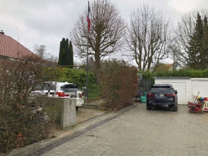 Einfamilienhaus in Hohwacht, Lütjenburger Straße 48, mit Garage und gepflastertem Vorplatz, zwei Fahrzeuge, kahle Bäume, französische Flagge