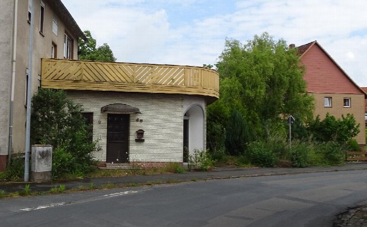 Vorderansicht eines Wohn-/Geschäftshauses mit weißem Ziegelmauerwerk, dunkler Tür, Bogenfassade und Holzbalkon am Leibnitzplatz 8 in Einbeck
