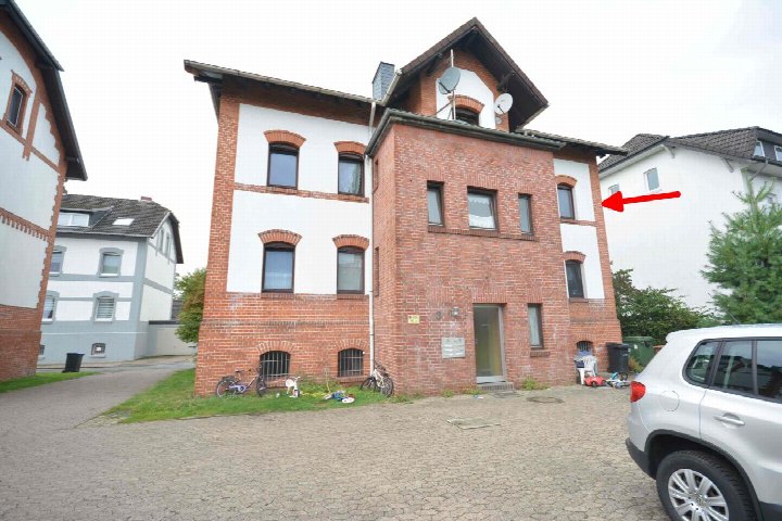 Vorderansicht eines mehrstöckigen Wohnhauses aus Backstein und Putz mit Eingang, Fenstern und gepflastertem Vorplatz in Weyhe, Richtweg 55