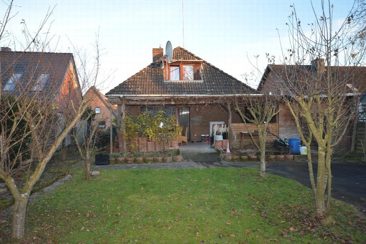 Rückgarten eines Einfamilienhauses mit Rasenfläche, kahlen Bäumen, Terrasse und Holzveranda. Syke, Plackenstraße 29