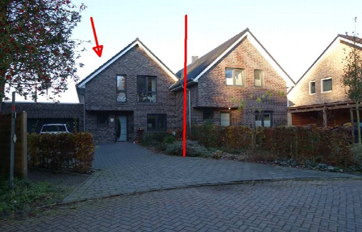 Vorderansicht einer Doppelhaushälfte mit Ziegelwand, Eingangstür, Fenstern und gepflastertem Vorplatz in Edewecht