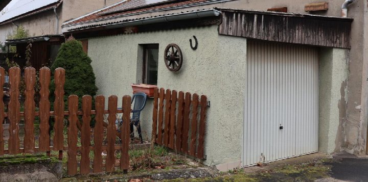 Garage mit weißer Rolltür an einem verputzten Gebäude, vorne Holzzaun und Gartenbereich, Nabburg, Unterer Weinberg 10