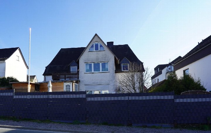 Zweifamilienhaus in Meschede, Lagerstr. 27, mit dunklem Dach, weißen Fassaden und Vorgartenzaun unter klarem Himmel