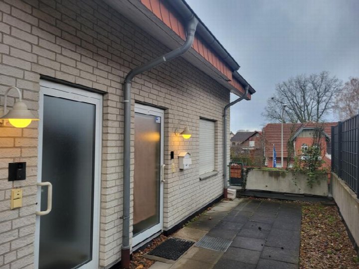Eingangsbereich einer Eigentumswohnung mit zwei Türen, Außenleuchten und gepflastertem Weg in Paderborn