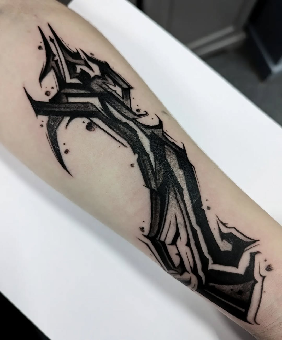 Bold angular black geometric shards wrap forearm with tension