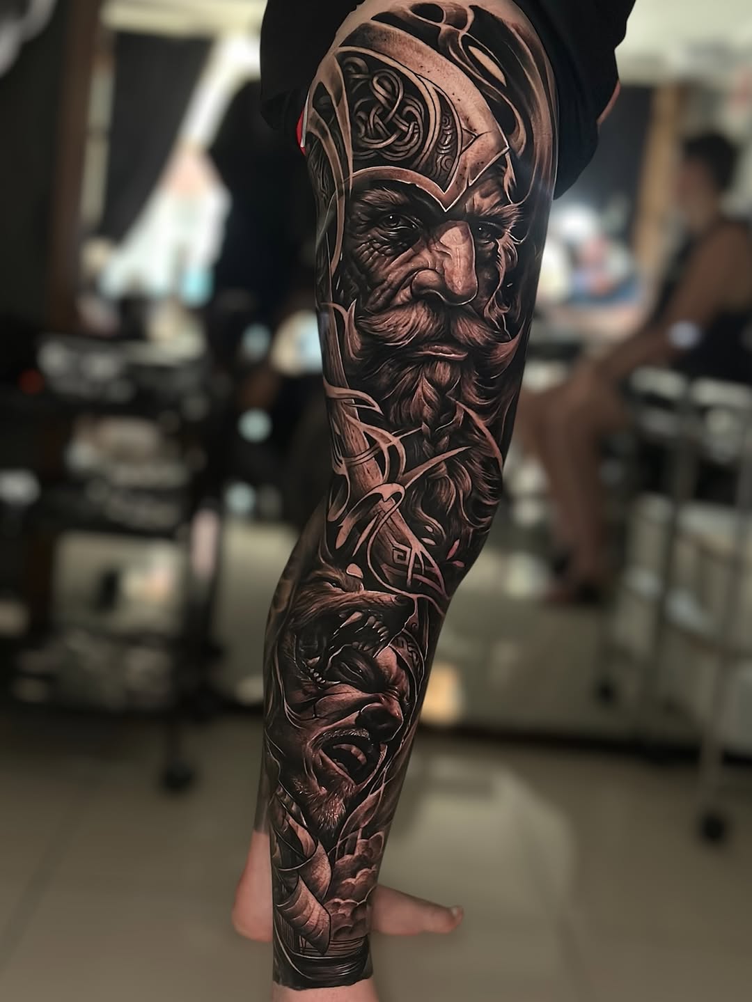 Hyper-detailed black-and-gray leg sleeve with Odin-like elder and wolves