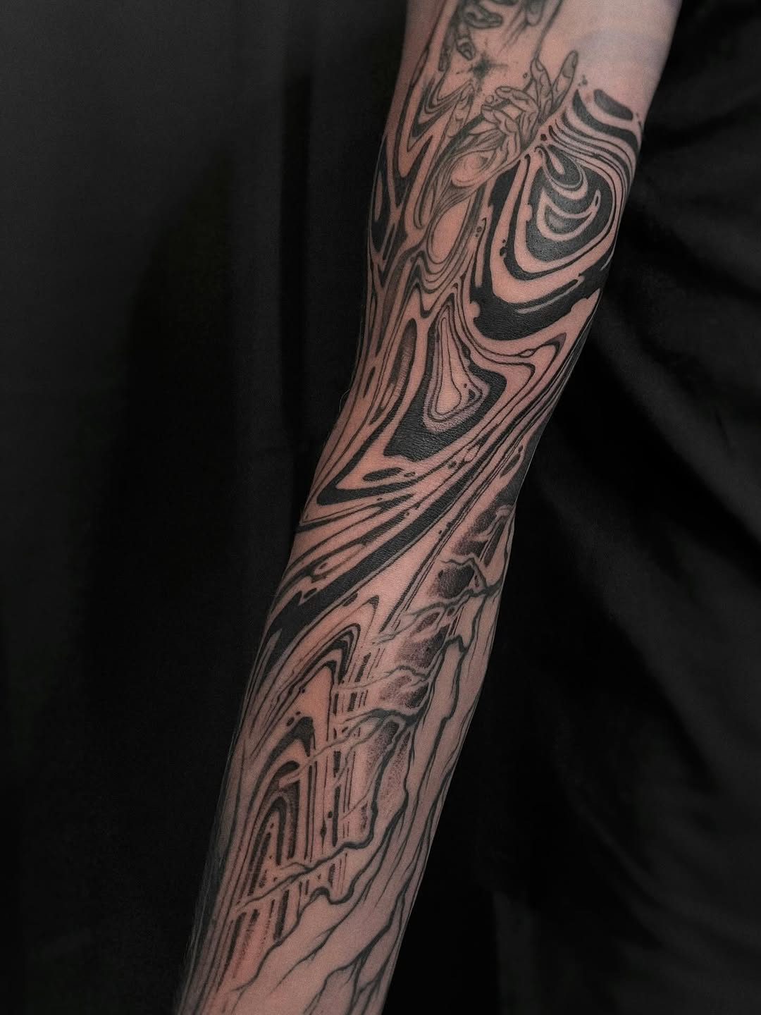 Intricate blackwork marbled swirl wraps the forearm.