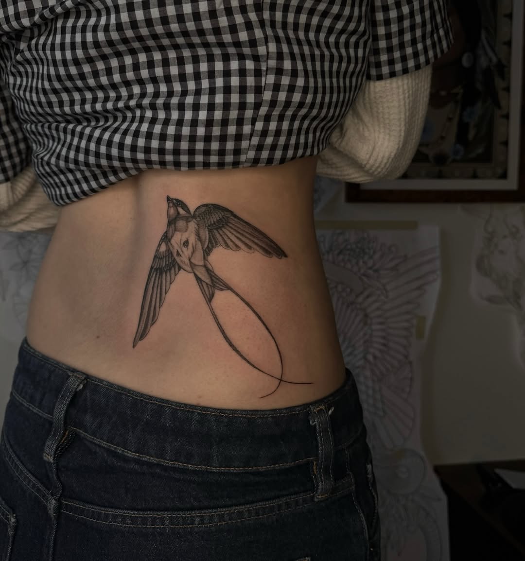 Delicate swallow in fine-line blackwork on ribs