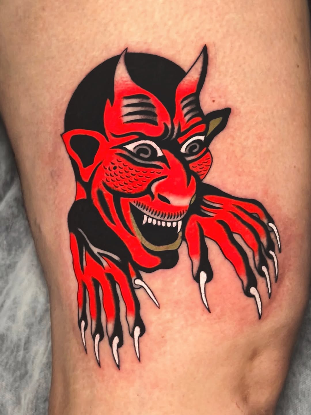Bold red demon head with horns and clawed hands