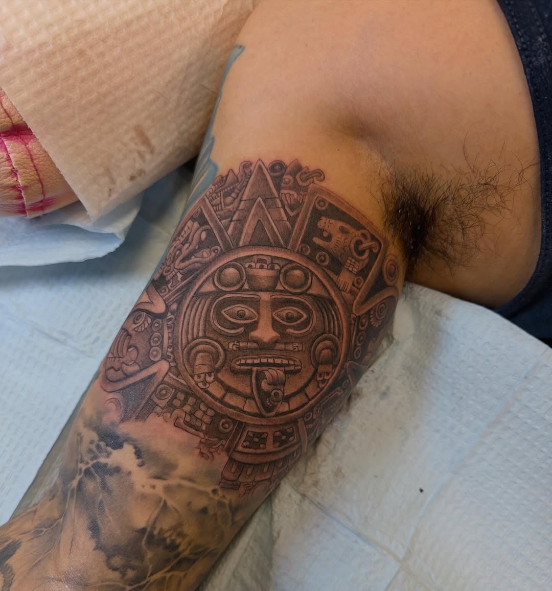 Intricate Aztec calendar tattoo with bold black shading