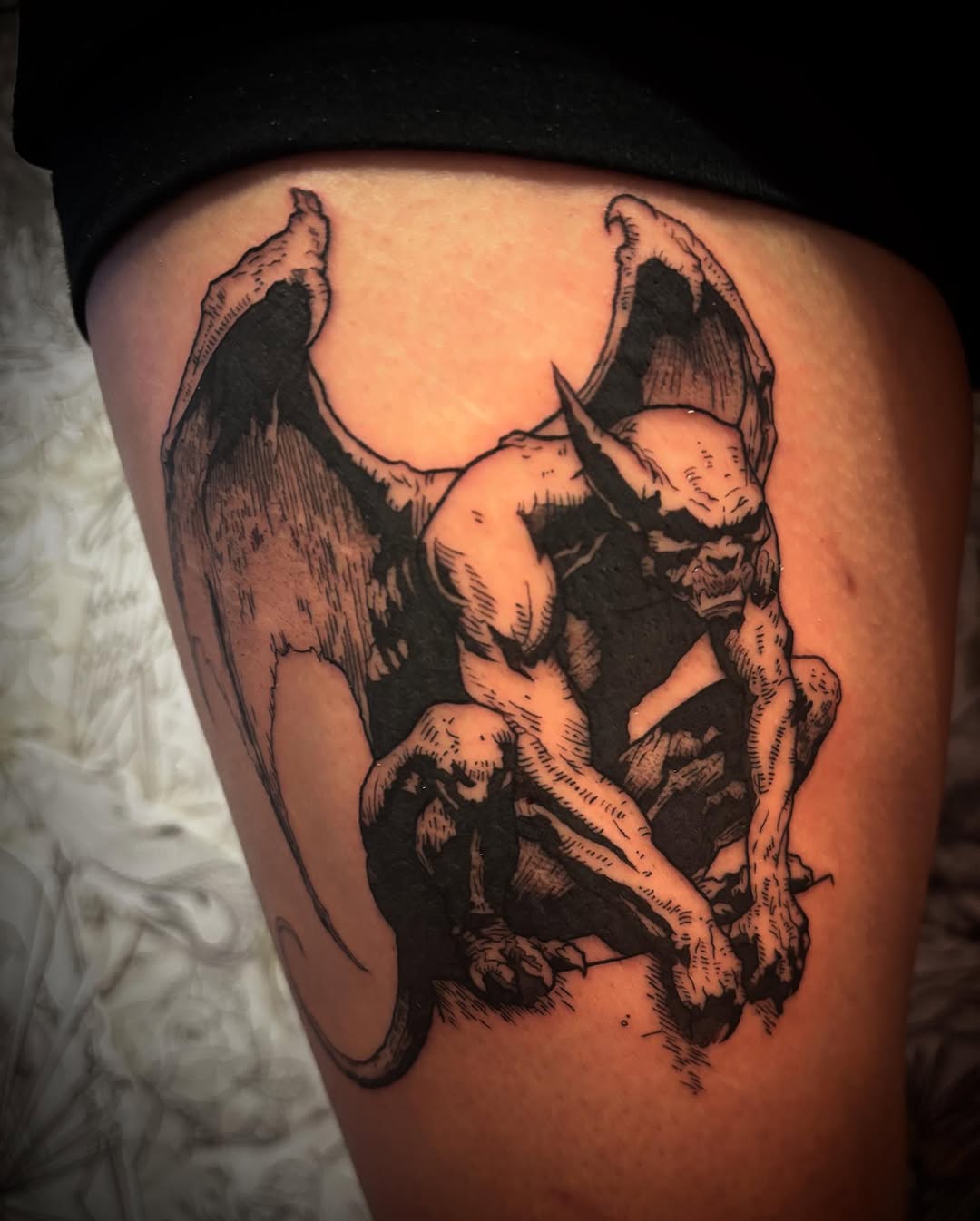 Bold blackwork gargoyle crouching on jagged rock, wings spread.