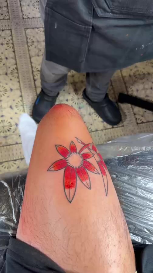 Bold red floral tattoo with crisp black outlines.